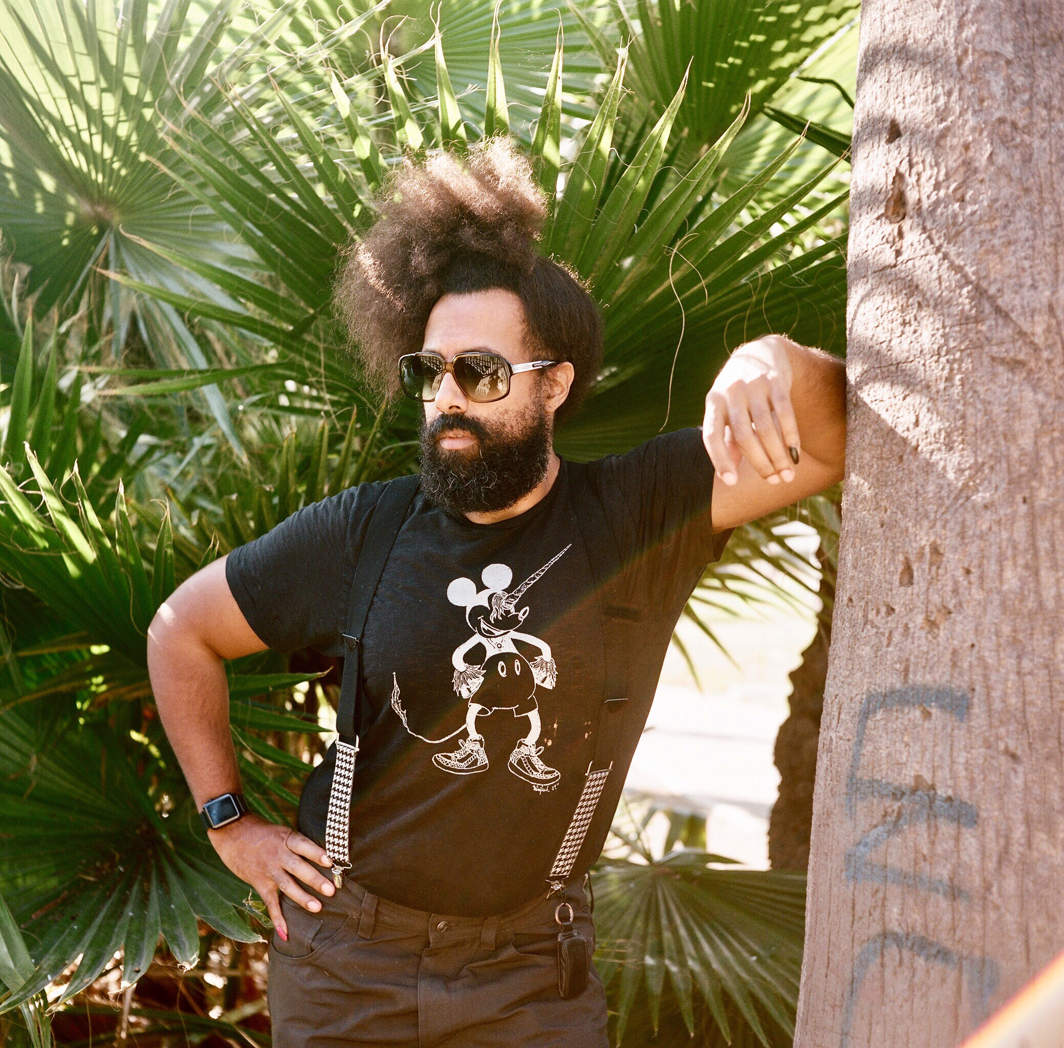 Reggie Watts leaning on a tree